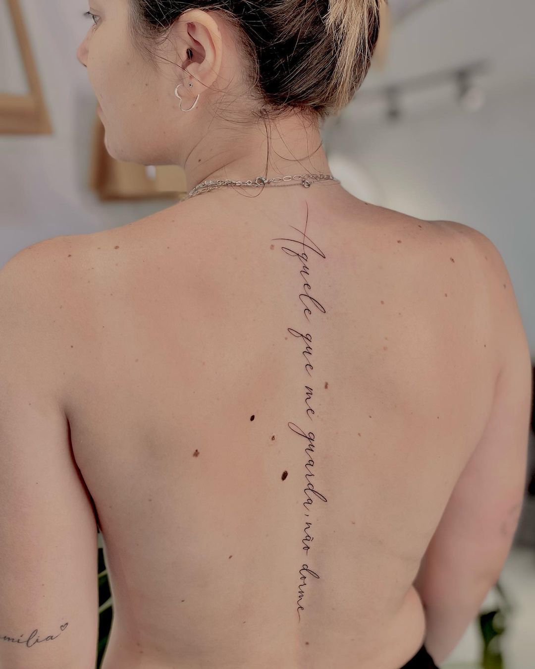 tatuagem de frase vertical na coluna vertebral