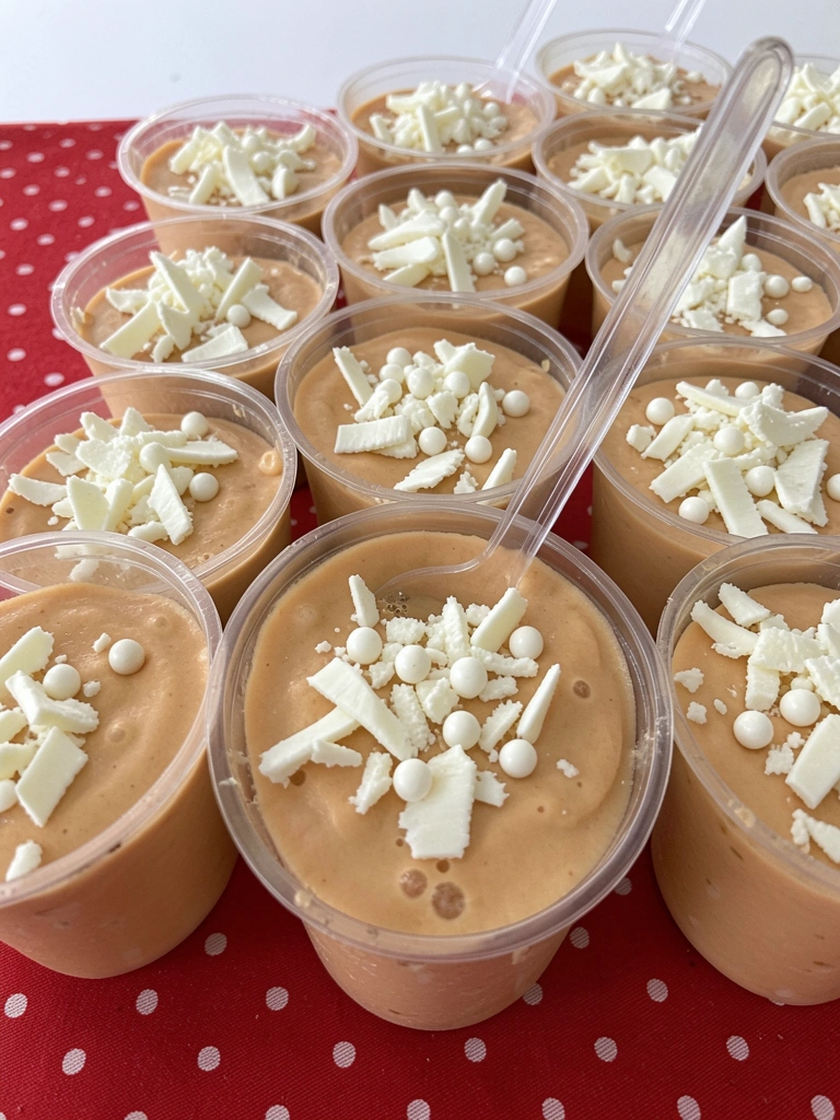 Brigadeiro de colher branco em copo de vidro, com raspas de chocolate na superfície.
