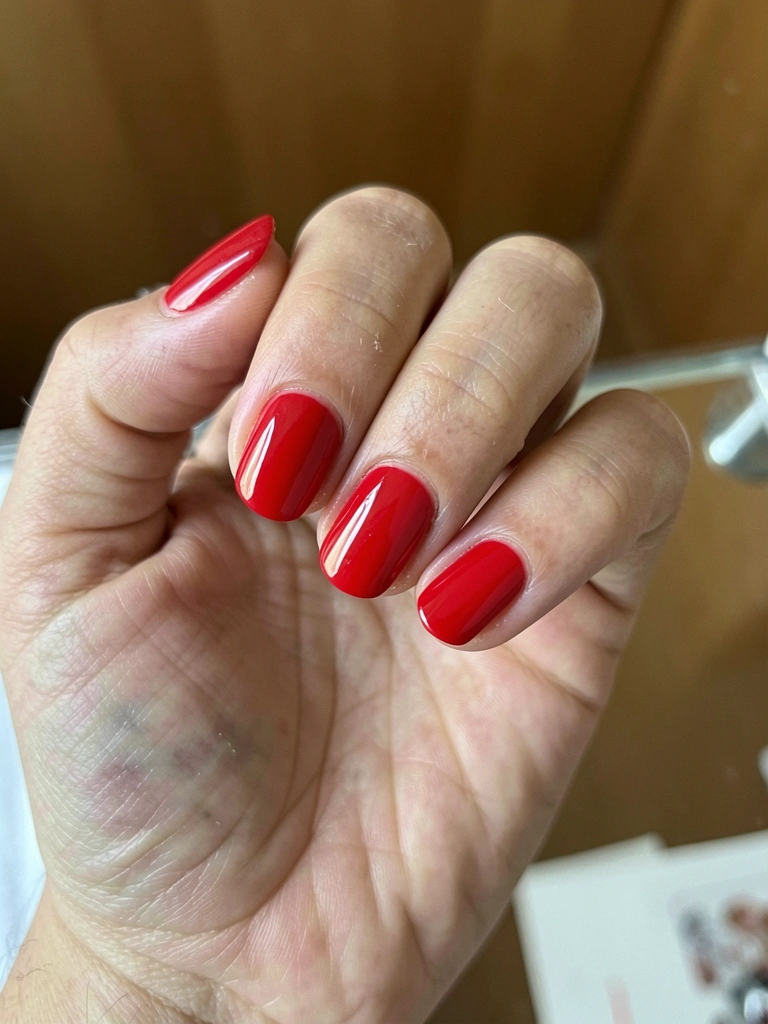 Unhas curtas em formato squoval com esmalte vermelho clássico e acabamento brilhante.