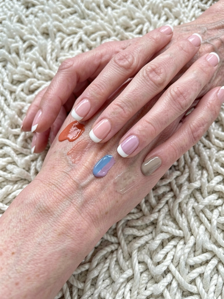 Pulso com veias aparentes e três amostras de esmalte em tons quente, frio e neutro