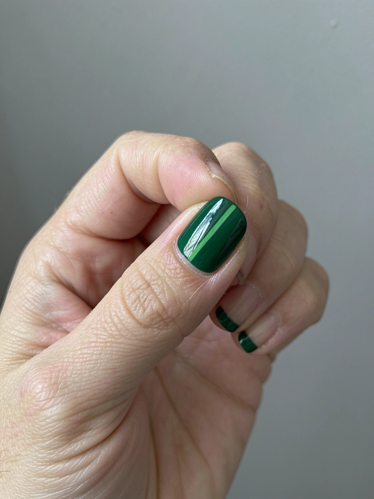 Unhas verdes com detalhes brancos no anelar