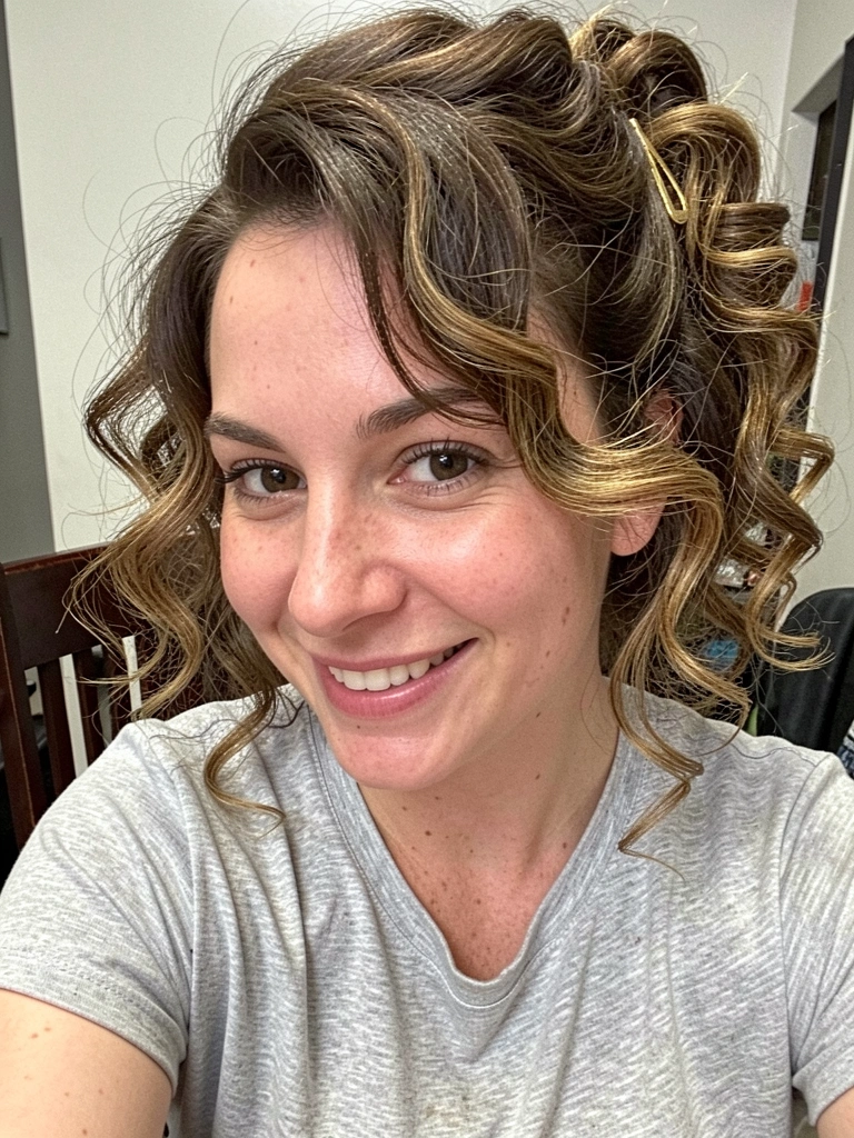 Cabelo cacheado preso lateralmente com presilha dourada, cachos definidos.