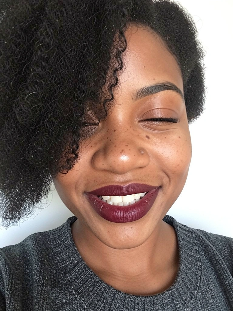 Mulher negra de perfil com cabelo 4C curto chanfrado, fundo claro.
