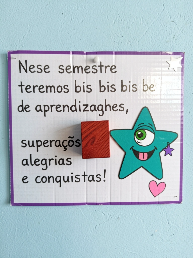 Ursinho de biscuit sentado com mochila nas costas e caderno aberto ao lado.