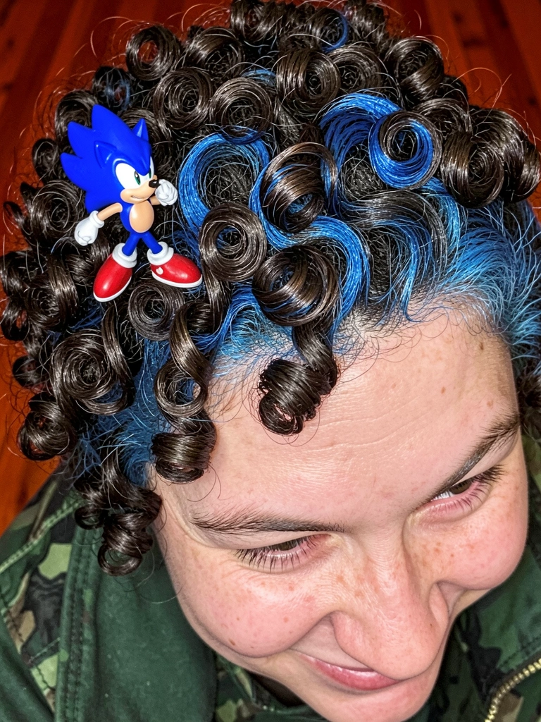 Mãos aplicam gel em cabelo molhado, com secador ao lado.