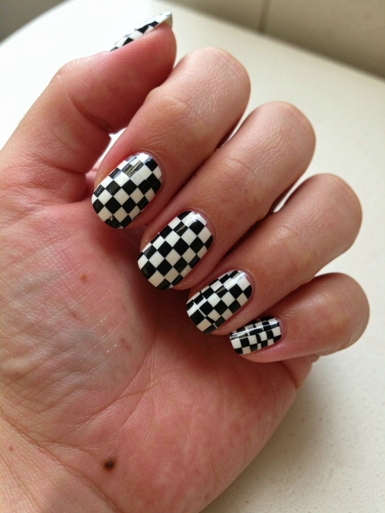 Unhas decoradas com padrão xadrez vermelho e branco.
