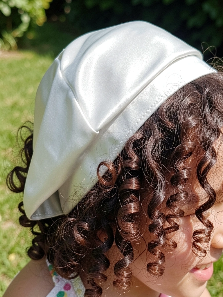 Touca de cetim e fronha de seda sobre cabelo cacheado.
