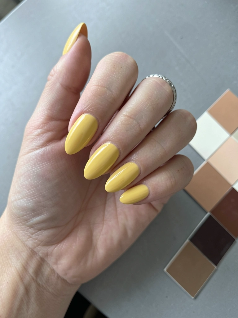Unhas pintadas de amarelo manteiga ao lado de amostras de pele.