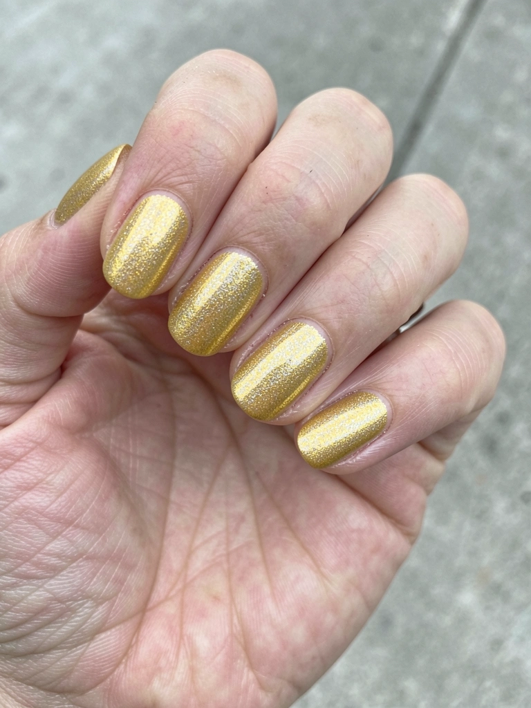 Mãos com esmalte amarelo manteiga sobre fundo neutro, luz natural suave.