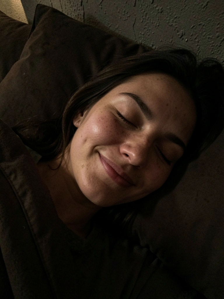 Mulher dormindo tranquilamente na cama, com iluminação suave vinda de uma luz noturna.