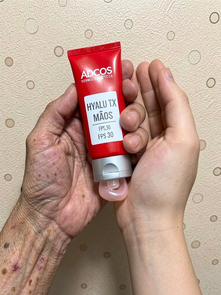 Mão jovem ao lado de mão envelhecida com rugas e manchas senis.