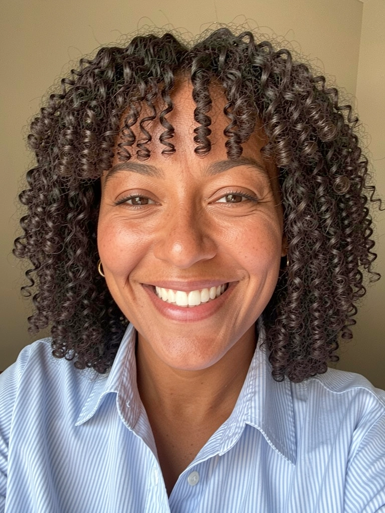 Cabelo cacheado cortado em camadas com formato arredondado e franja lateral.
