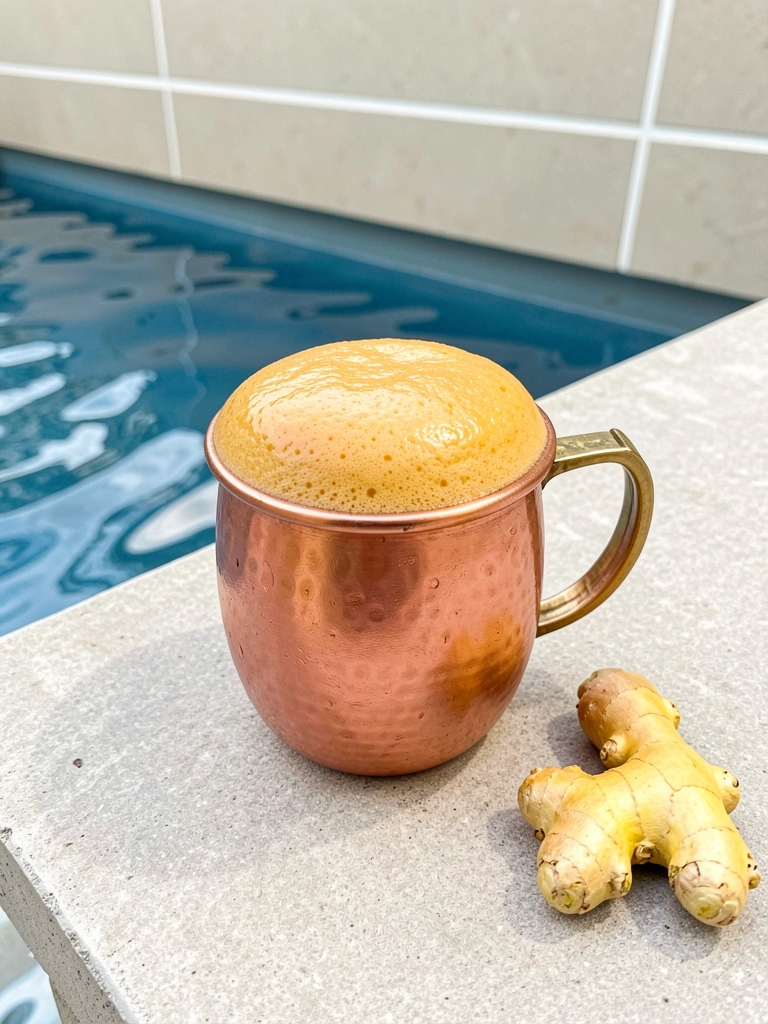 Espuma de gengibre dourada sobre um coquetel Moscow Mule em copo de cobre.